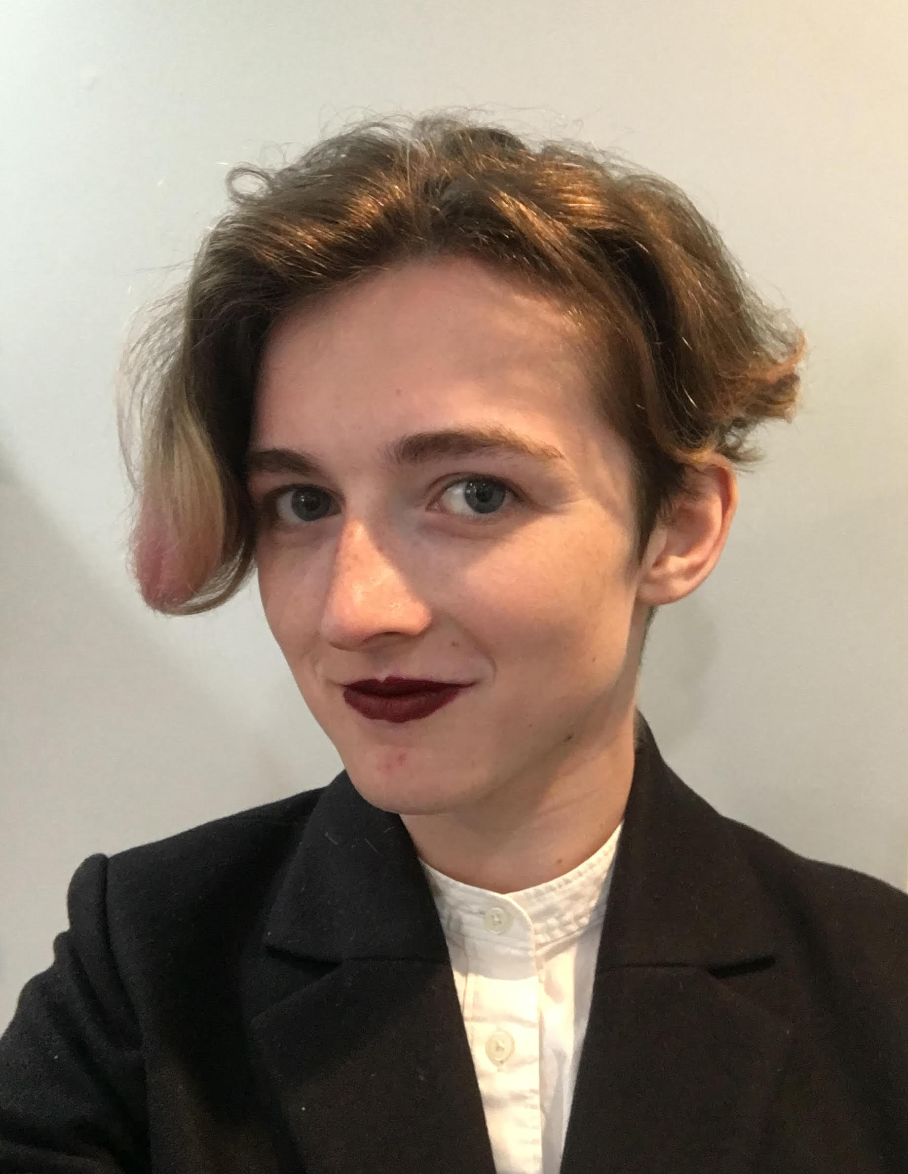 A picture of Ani Hopkins. She has short hair and is wearing
      dark maroon lipstick, a white blouse, and a blazer. She is smiling and
      looking at the camera.